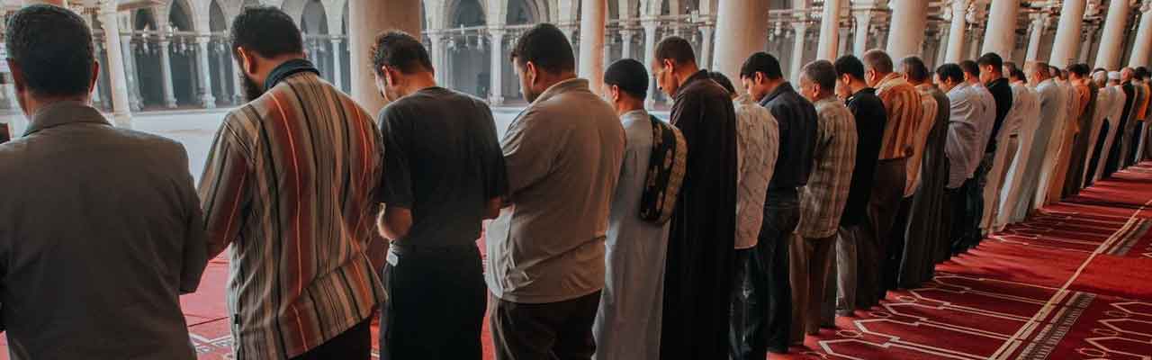women pray in rows parallel to men